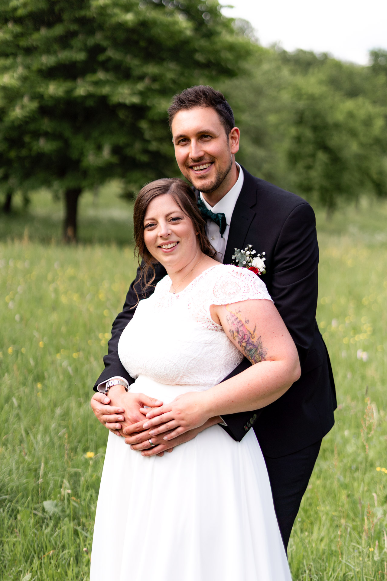 Kevin umarmt Lisa von hinten auf einer Blumenwiese